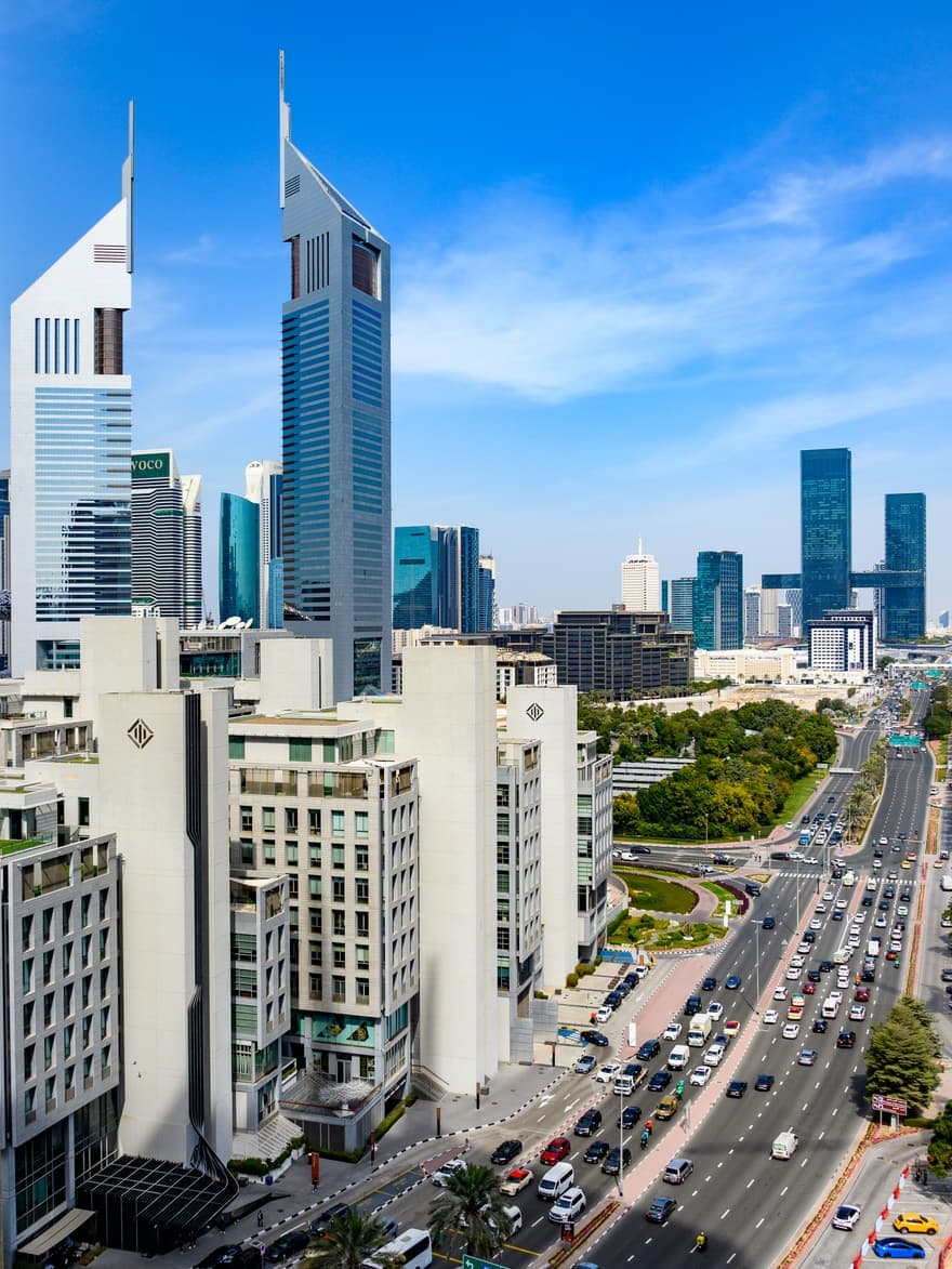 Emirates Towers on Sheikh Zayed Road, Dubai, with the DIFC skyline behind and heavy traffic threading through downtown