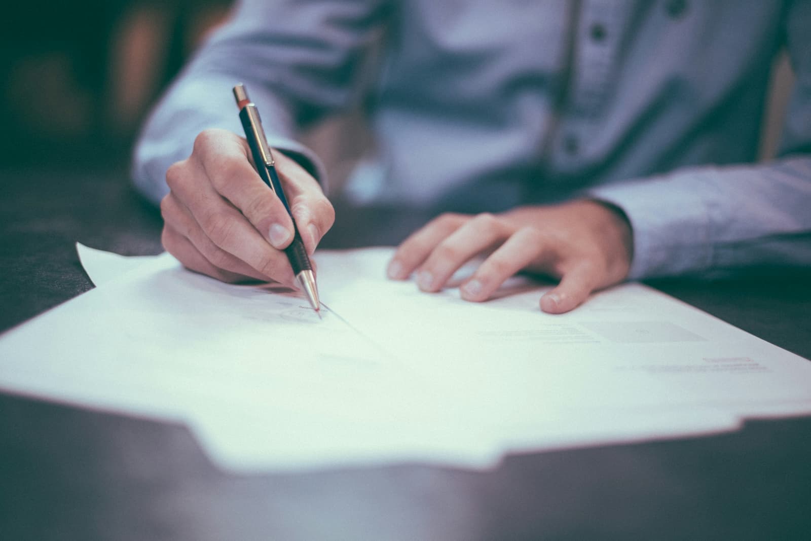Hands signing a document at a desk